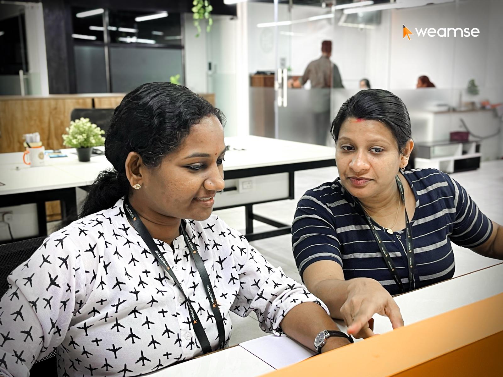 Two colleagues reviewing work together at a WEAMSE workstation